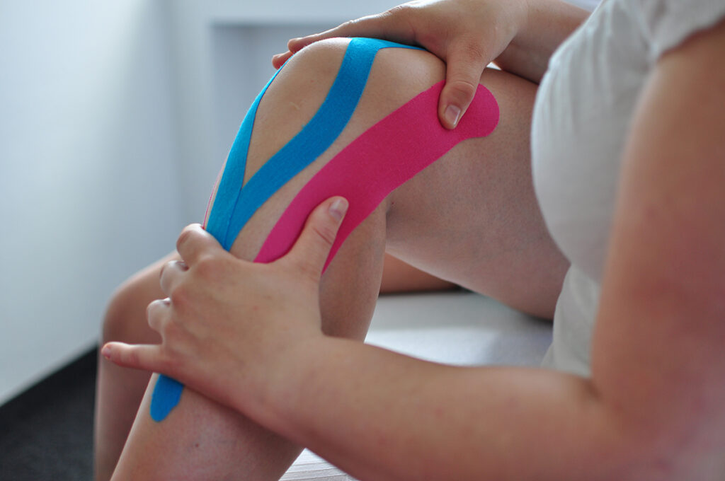 applying athletic tape to knee for support